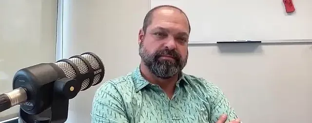 Dr. Sam McGough at the microphone while recording an episode of The Hunt for Success