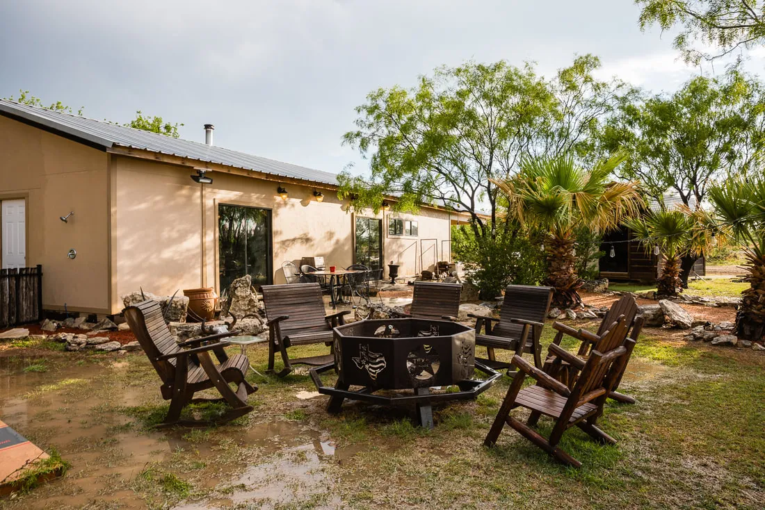 The ranch lodge exterior with a fire pit and seating at dusk